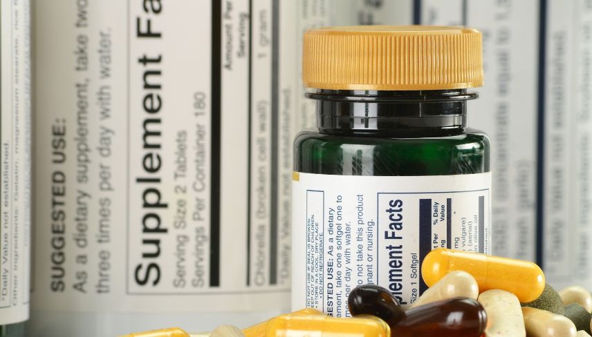 Food supplement bottles and capsules displayed against a background of supplement facts labels.